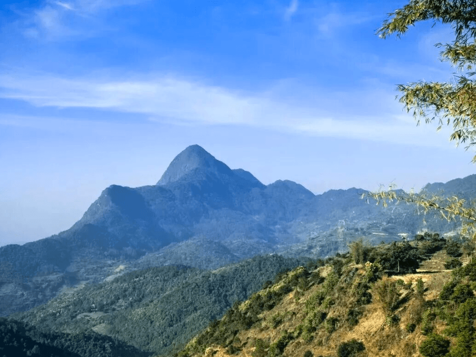 A high mountain and tea-growing slopes in Yunnan under a clear blue sky
